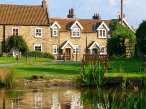 Brantingham的住宿－Pond View Cottage，一座老房子,前面有一个池塘