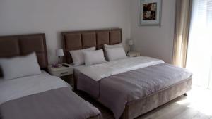 a bedroom with two beds and two tables with lamps at Lago d'argento sobe in Veliko Gradište