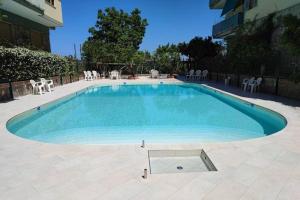 une grande piscine avec des chaises et un bâtiment dans l'établissement Garden House Giulia, à Sorrente