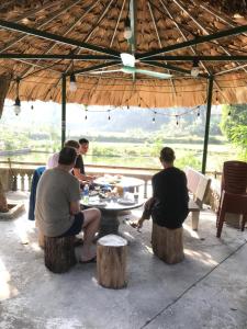 Un groupe de personnes assises autour d'une table sous un parapluie dans l'établissement VuLinh Family Homestay, à Yên Bình