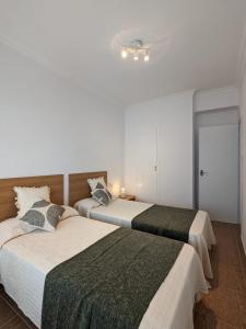 two beds in a room with white walls at Terraza con vistas al mar Parking privado 120 mts, junto a la playa in Cullera