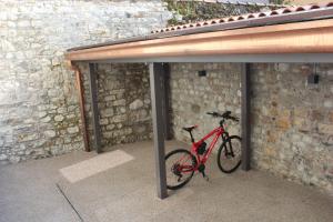 ein rotes Fahrrad, das neben einer Ziegelwand parkt in der Unterkunft Il Giardino Segreto in Cividale del Friuli