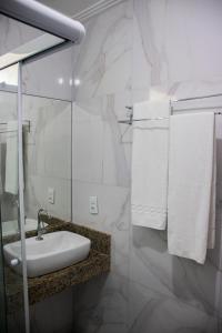 Baño blanco con lavabo y toallas en Duna´s guest house en Salvador