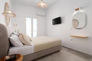 a white bedroom with a bed and a mirror at Naxian sun apartment in Naxos Chora