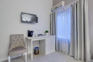 a white desk with a chair and a television on a wall at Well Sleep Hotel in Almaty
