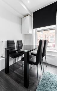 a dining room with a black table and chairs at Aldgate Flats in London