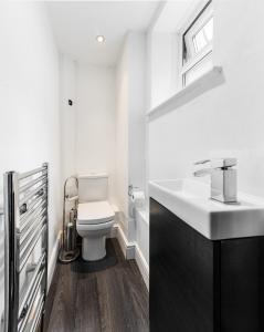 a bathroom with a white toilet and a sink at Aldgate Flats in London