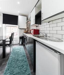 a kitchen with white cabinets and a green rug at Aldgate Flats in London