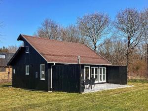 a black house with a brown roof on a field at Holiday home Hovborg XI in Hovborg