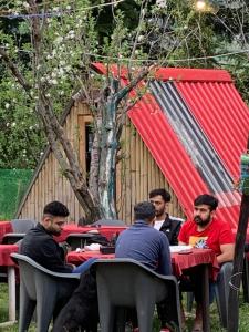 un grupo de hombres sentados en una mesa frente a un edificio en TravelON Manali Glamping Resort en Manāli