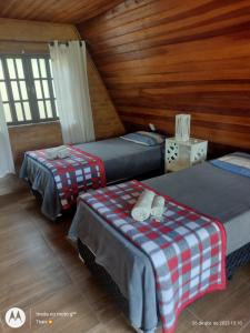 Duas camas num quarto com paredes de madeira em Pousada nossa senhora em Aiuruoca