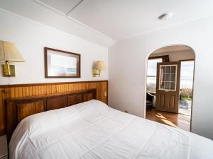 1 dormitorio con cama blanca y espejo en Oceanside Ocean Front Cabins, en Oceanside