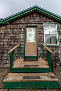 Casa con puerta marrón y porche de madera en Oceanside Ocean Front Cabins, en Oceanside