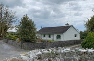 ein weißes Haus hinter einer steinernen Mauer in der Unterkunft Bridgeview B&B in Ennis