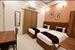 a hotel room with two beds and a desk at Kings Mysuru hotels - SGH in Mysore