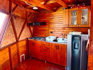 cocina con armarios de madera y nevera en Glamping San Sebastian, en Suesca