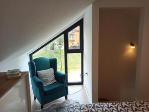 a blue chair sitting in a room with a window at Bruka house Vrujci in Gornja Toplica