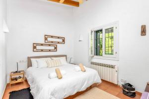 a white bedroom with a bed and a window at Sa Figuera de Moru in Trebeluger