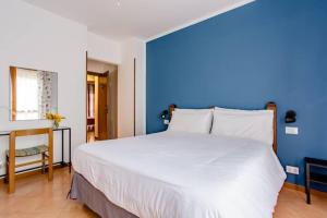 1 dormitorio con 1 cama blanca grande y pared azul en B&B Le Palme, en Grottammare