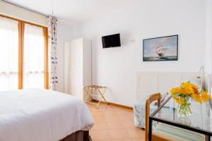 a white bedroom with a bed and a vase of flowers at B&B Le Palme in Grottammare