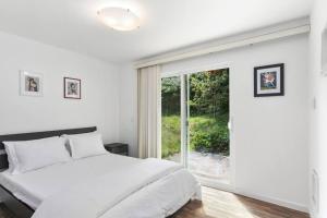 a white bedroom with a bed and a large window at Epicurean remodel in central location. in Seattle