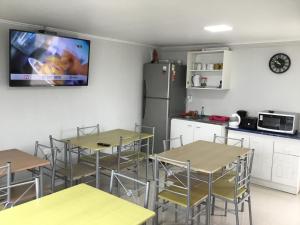 a room with tables and a kitchen with a tv at Hostal Playa Brava in Caldera