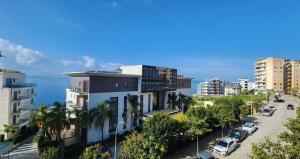 a city street with buildings and the ocean in the background at 3B Suites Boutique Hotel in Sarandë
