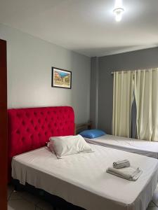 a bedroom with two beds with a red headboard at Pousada Vovo Valdir in Itapema