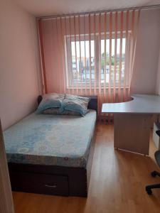 een kleine slaapkamer met een bed en een bureau bij Spacious 4 rooms downtown apartment in Pitesti in Piteşti