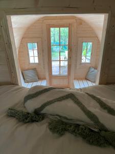 Cama en habitación de madera con 2 ventanas en Le Hameau, en Florent-en-Argonne