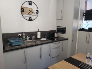 eine Küche mit einem Waschbecken und einer Uhr an der Wand in der Unterkunft Studio 6 in Le Boupère