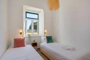 two beds in a room with a window at Cozy Apartment with Patio near Carcavelos Beach in Carcavelos