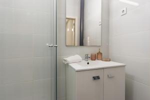 a white bathroom with a sink and a mirror at Cozy Apartment with Patio near Carcavelos Beach in Carcavelos +34 photos