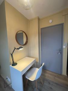 ein Zimmer mit einem Schreibtisch, einem Stuhl und einem Spiegel in der Unterkunft Petit Studio Centre-Ville n°14 in Besançon