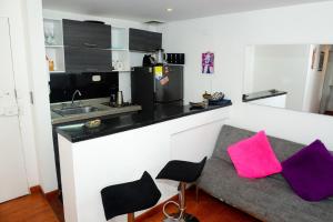 uma cozinha com um balcão e um sofá com almofadas roxas em Acogedor Apartamento La Candelaria 2 Habitaciones EC52 em Bogotá