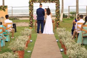 Uma noiva e um noivo a caminho do altar na cerimónia de casamento. em EnseadaPrime eventos e casamentos beira-mar na Praia Enseada dos Corais em PE em Cabo de Santo Agostinho