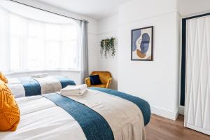 a bedroom with two beds and a chair at Stylish Newcastle Gem - Sleeps 9 - Parking in Newcastle upon Tyne