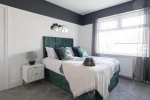 a bedroom with a bed with a green headboard and a window at Stylish Newcastle Gem - Sleeps 9 - Parking in Newcastle upon Tyne