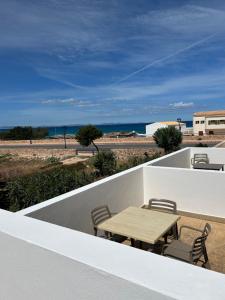 een tafel en stoelen op een balkon met uitzicht op het strand bij Apartamento Es Calo (Edificio Cavall de Llevant) in Es Calo