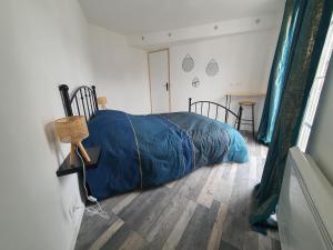 um quarto com uma cama com um cobertor azul no chão em Appartement meublé, bord de seine em Duclair