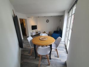 uma sala de jantar com uma mesa de madeira e cadeiras brancas em Appartement meublé, bord de seine em Duclair