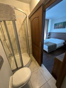 a bathroom with a shower and a toilet and a bed at Paperon Hotel in Limonlu
