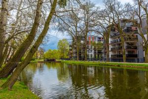 a river in a park with a building and trees at Premium Wrocławska Apartament Parking in Bydgoszcz