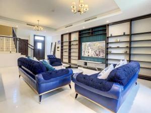 a living room with two blue couches and a television at Key View - Casa Flores Villa in Dubai