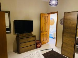 a living room with a television on a wooden dresser at the valley in Il-Gżira