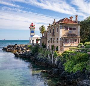 a house on a cliff next to a lighthouse at Cozy Apartment with Patio near Carcavelos Beach in Carcavelos