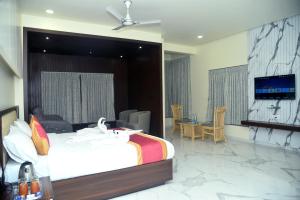 Hotel Royal Inn في Mudhol: غرفة نوم فيها سرير وتلفزيون