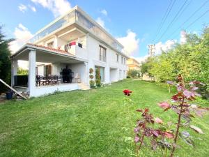 ein weißes Haus mit einem Garten mit einer Blume in der Unterkunft Airport Villa hotel in Arnavutköy