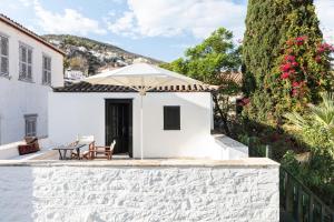 a white house with a table and an umbrella at Bratsera Boutique Hotel in Hydra