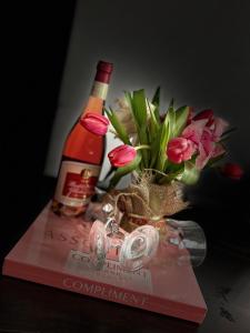 - une bouteille de vin et un vase avec des fleurs sur un livre dans l'établissement Casa Lupascu, à Vatra Dornei